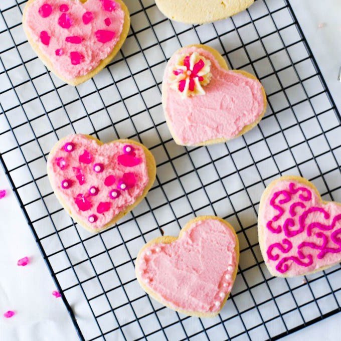 Low Carb Sugar Cookies on a baker's rack with sprinkles and a piping bag off to the side.